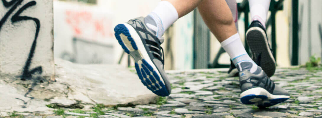 Corridore con calzini da corsa che fa jogging in città - focus sui piedi con il prodotto