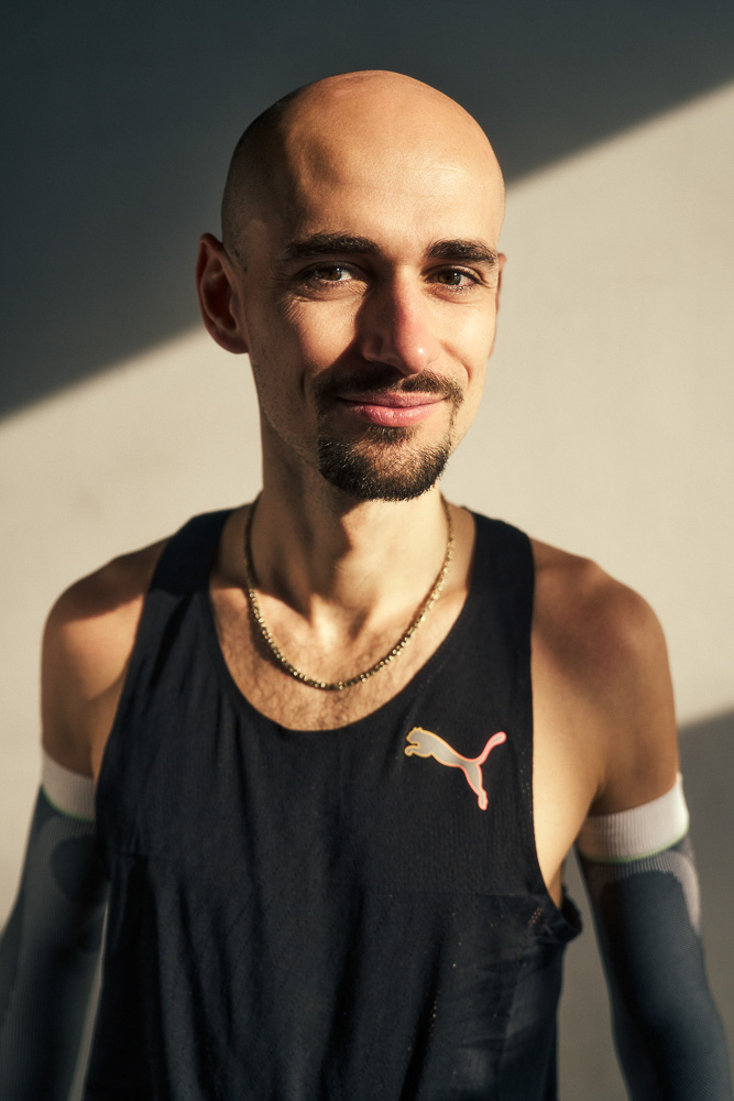 Ritratto di Hendrik Pfeiffer dopo l’allenamento. Ritratto del maratoneta Hendrik Pfeiffer in abbigliamento sportivo con maniche compressive, fotografato alla luce naturale dopo l’allenamento.