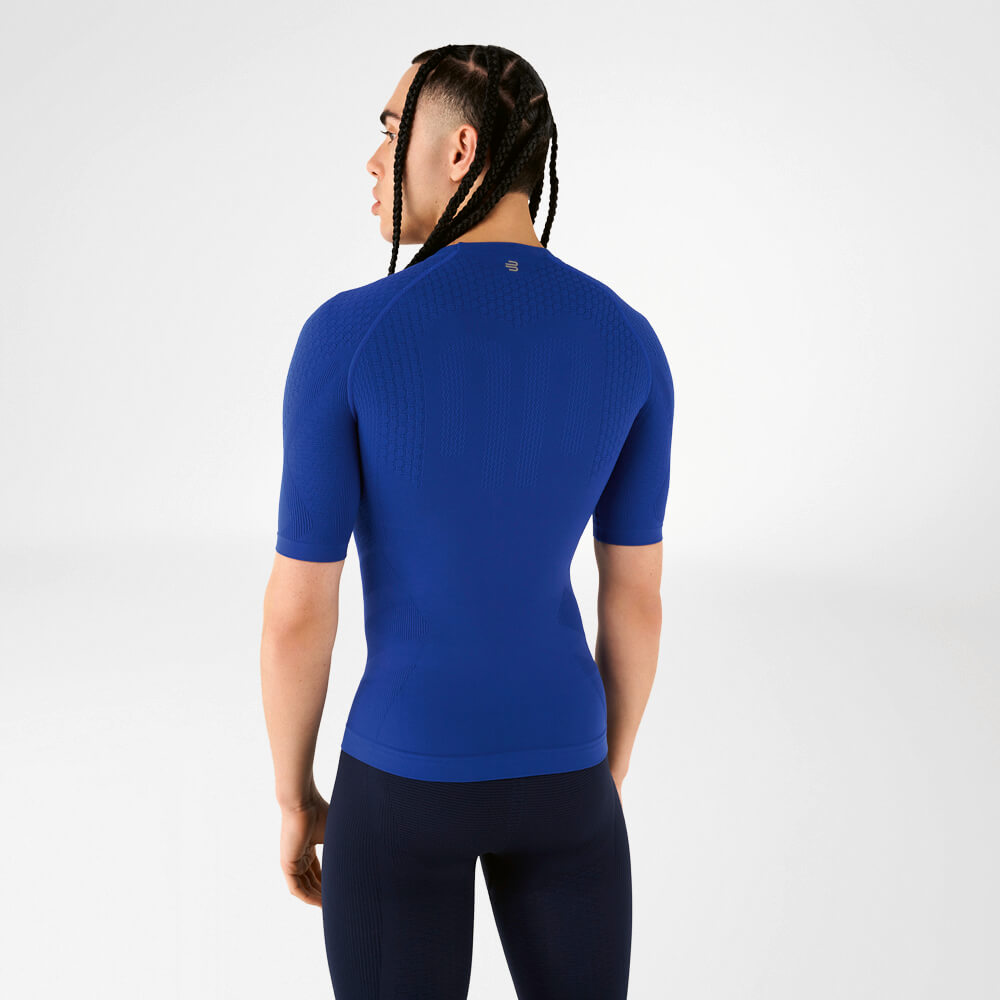 Un uomo indossa una maglia a compressione blu, di spalle alla fotocamera, guarda oltre la spalla.