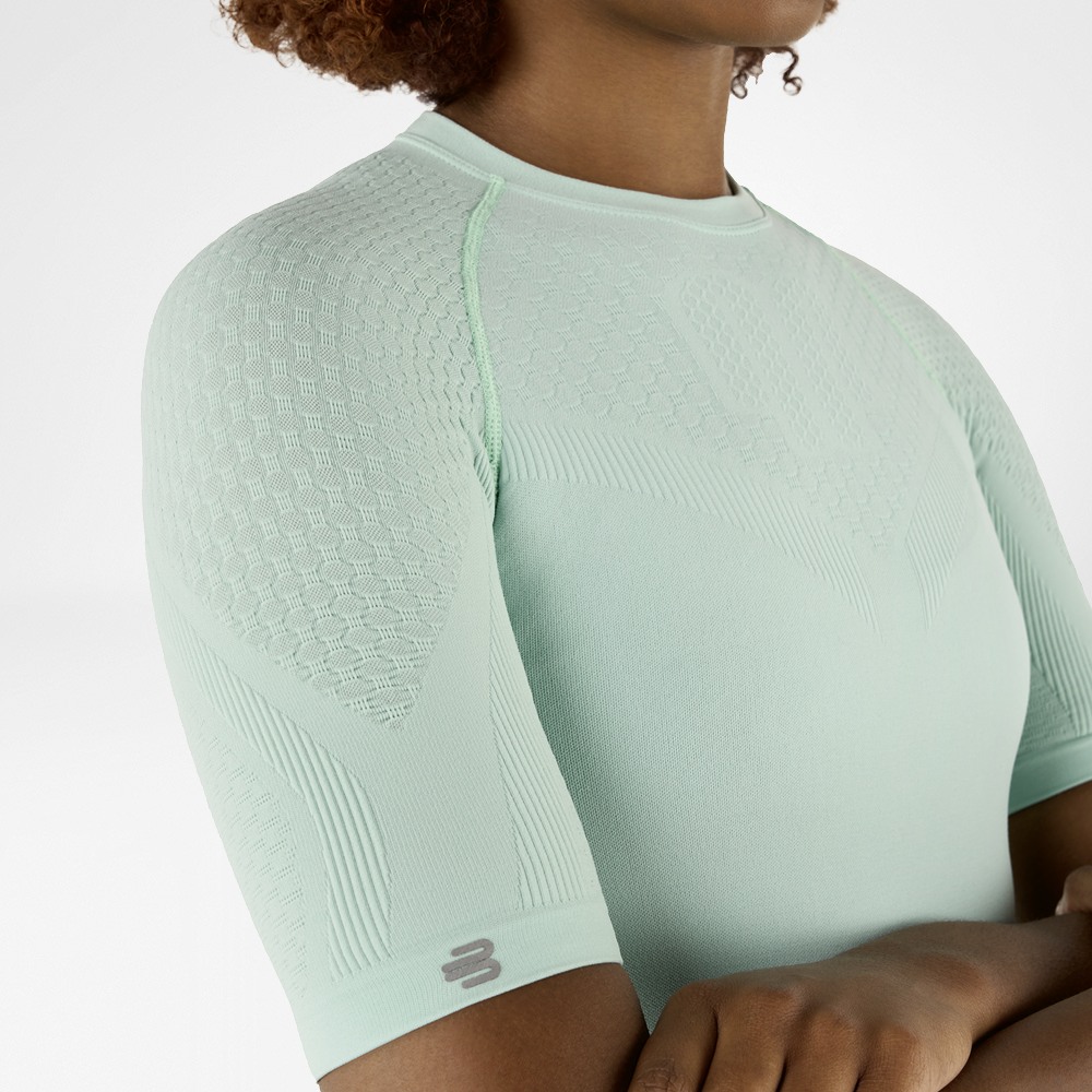 Primo piano laterale di una maglia a compressione verde menta con tessuto strutturato dettagliato sulla spalla e sul braccio.