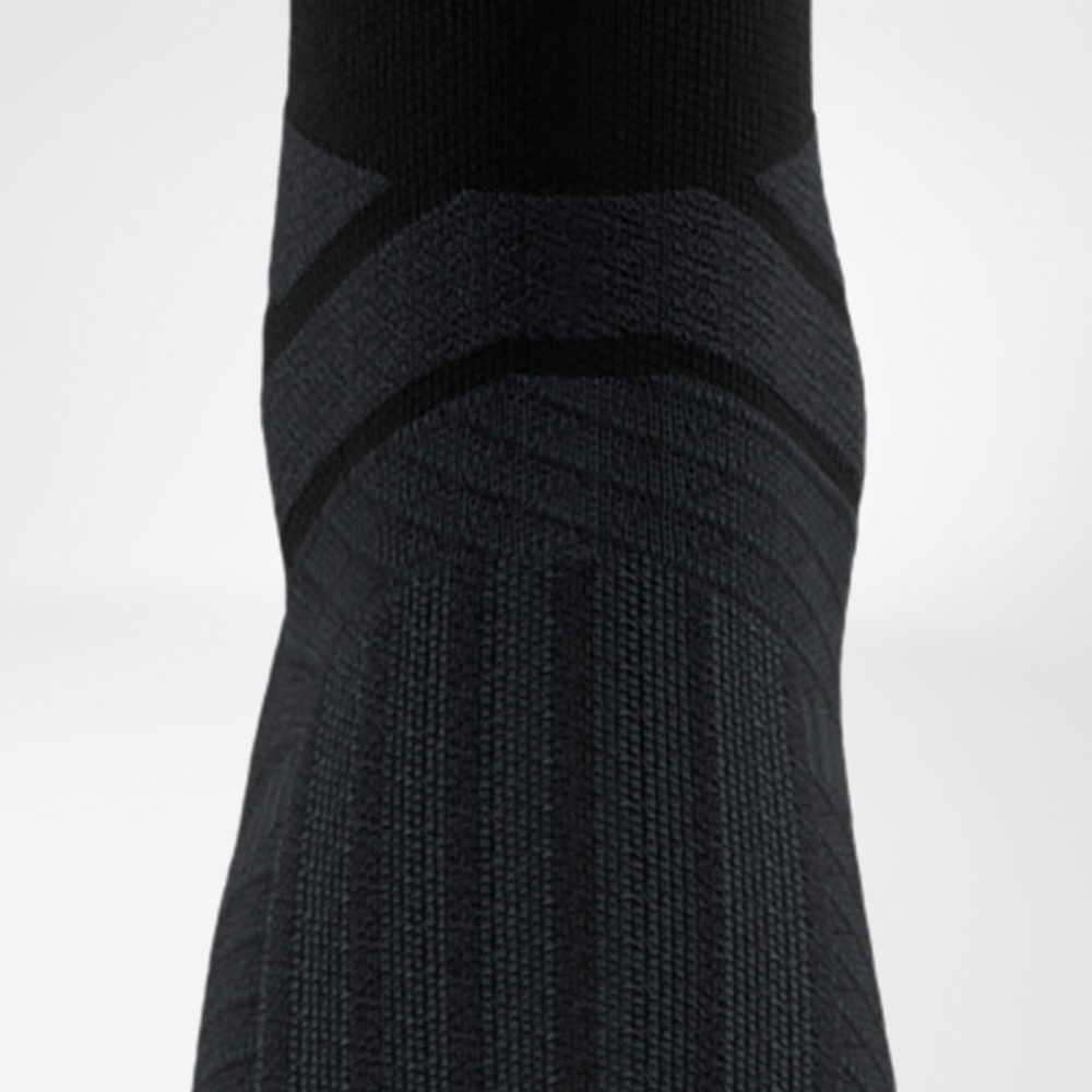 Primo piano del collo del piede di una calza a compressione nera con punti 3D per una distribuzione mirata della pressione e comfort durante l’allenamento.