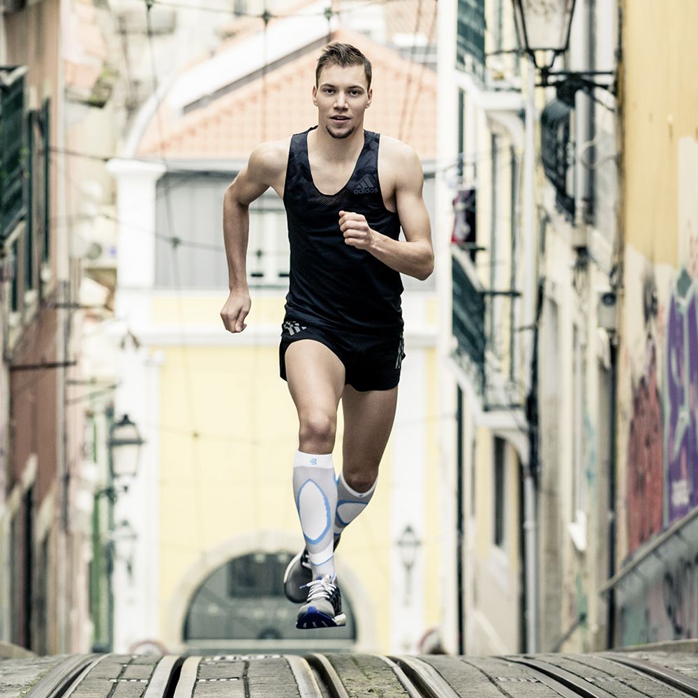 I corridori con calze a compressione per correre corrono una collina fino allo spettatore in una città