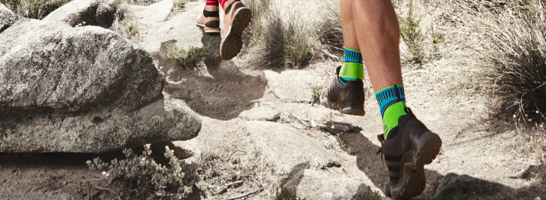 Sezione immagine di una persona che corre su una montagna rocciosa e indossa una benda alla caviglia su entrambi i piedi