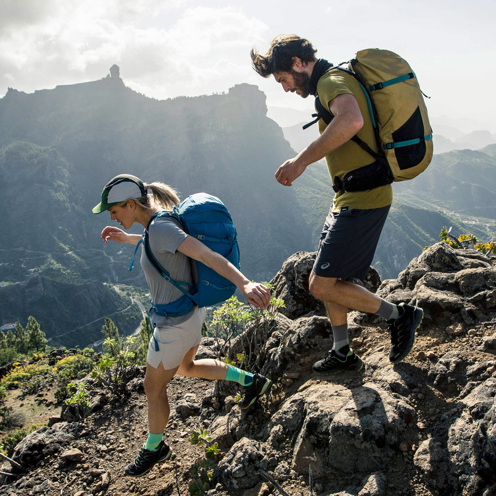 Escursionisti con calze da trekking che scendono dalla montagna davanti a un panorama montano