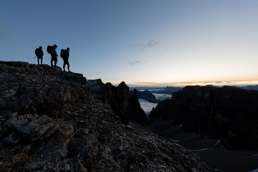 Escursionisti su una cima delle Dolomiti all'alba Silhouette di escursionisti su una cima delle Dolomiti all'alba o al tramonto. Sullo sfondo sono visibili nuvole e cime montuose.