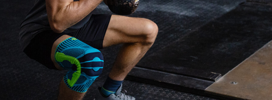 Kniebandage in fitness Gli atleti in palestra nello squat indossa una fascia per lo sport