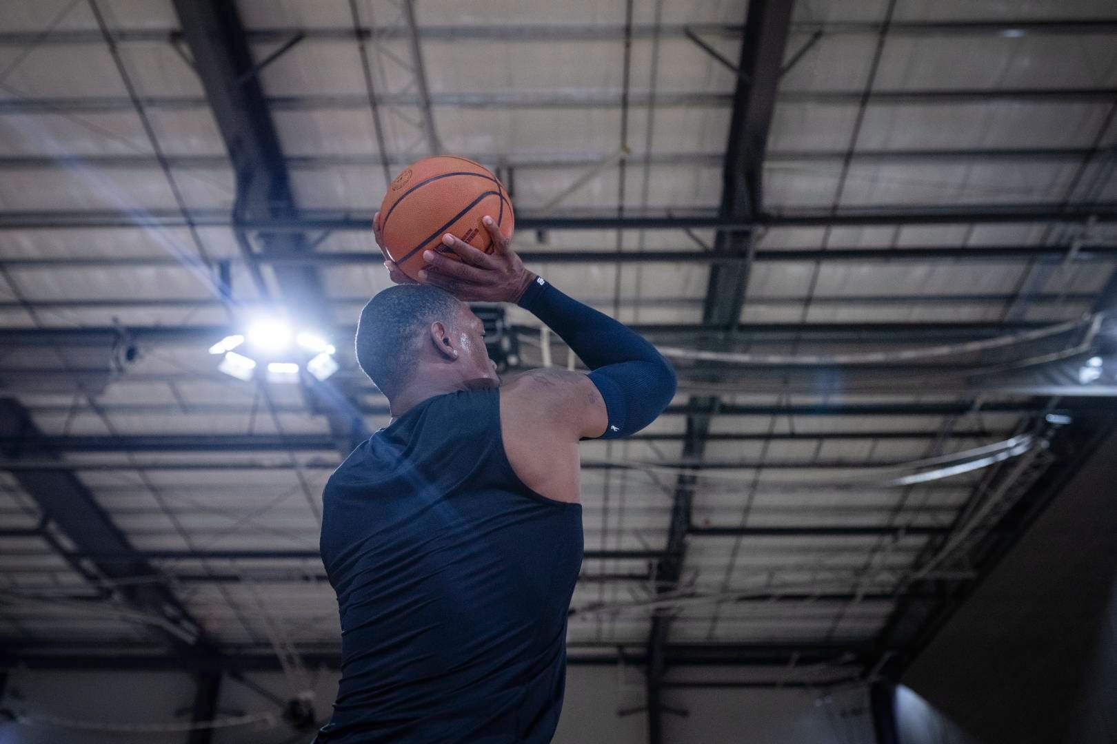 I giocatori di basket con un armatore blu in una sala sportiva iniziano con le mani sopra la testa fino al tiro