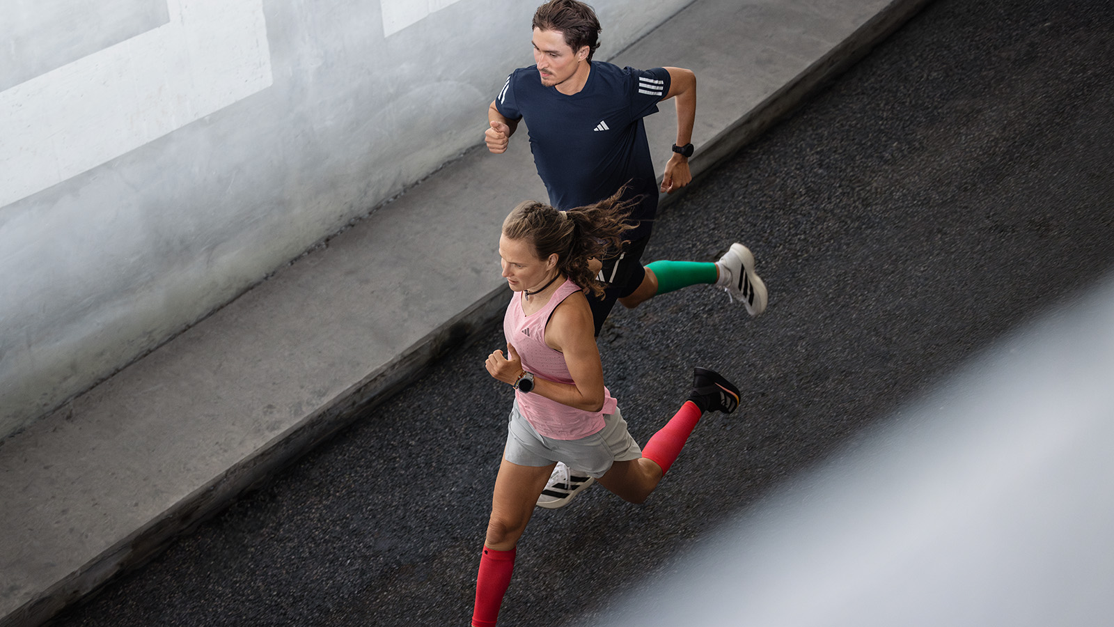 Piano di allenamento della maratona: il lungo periodo rilassato dovrebbe sempre costituire la base per il tuo allenamento Due corridori corrono accanto a un muro moderno nell'ambiente urbano e parlano