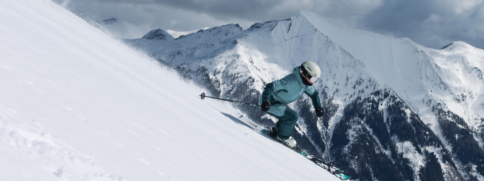 Skiing: dotato di prodotti nemici Bauer Gli sciatori guidano giù da un palo, ci sono montagne coperte di neve sullo sfondo