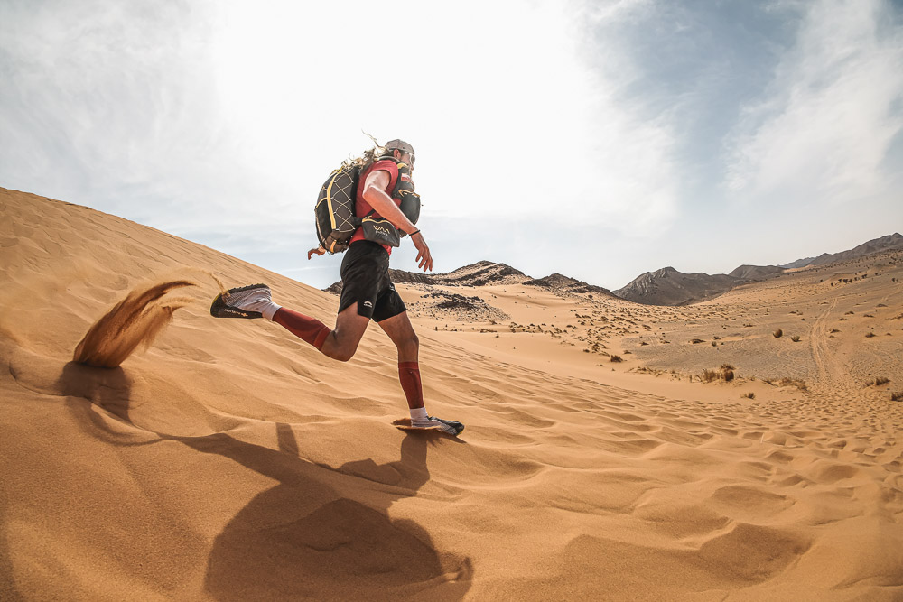 Ultrarunner mentre corre tra le dune in un vasto paesaggio desertico