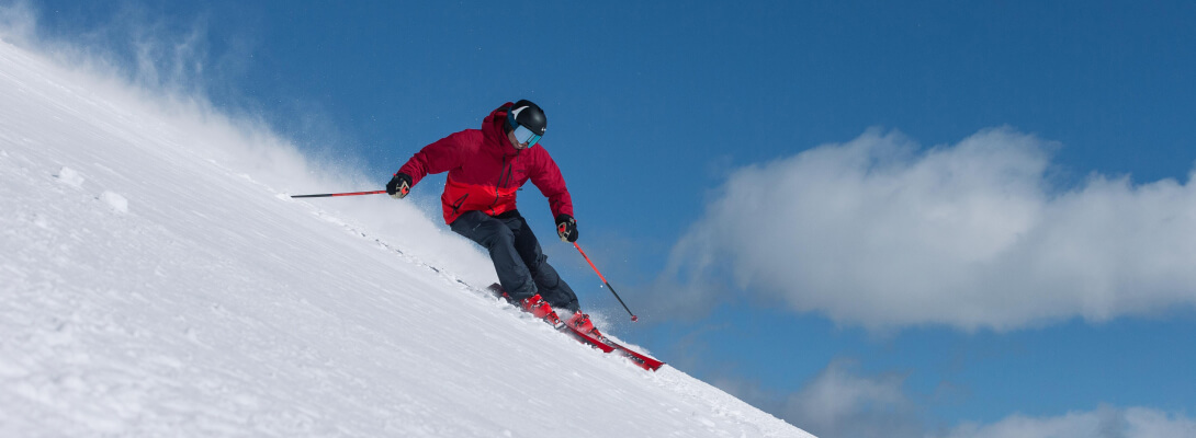 Merino Skisocken beim Alpine Ski Skifahrer mit roter Jacke im Pulverschnee bei Abfahrtsski
