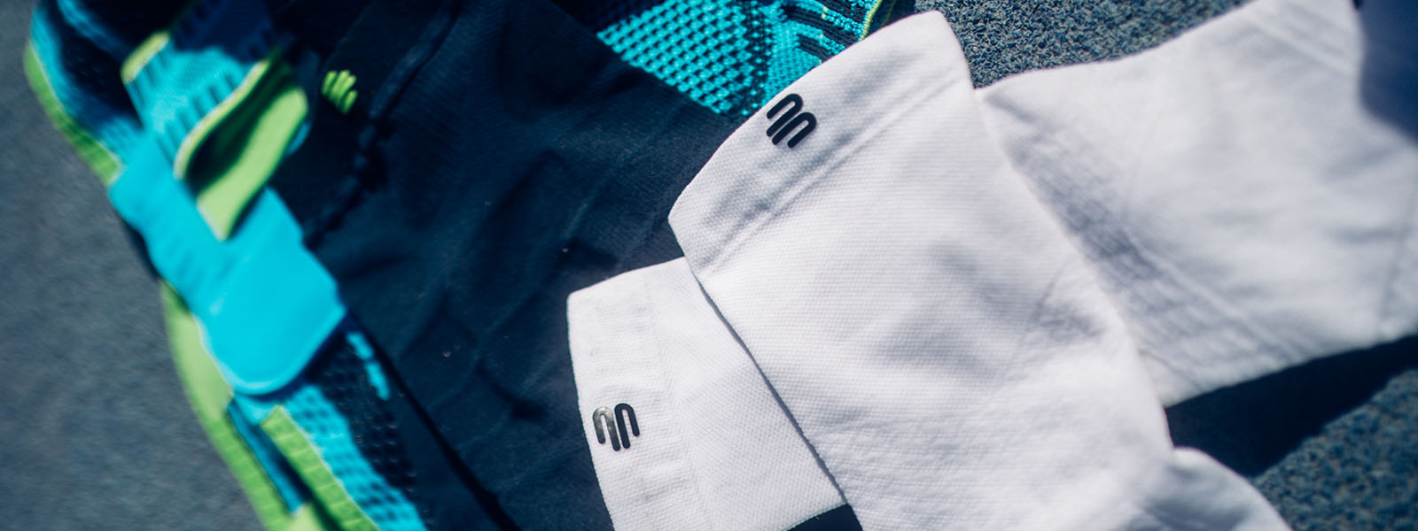 Prodotti Bauerfeind Sports – Abbigliamento a compressione di alta qualità per prestazioni ottimali Primo piano di vari prodotti Bauerfeind Sports, tra cui abbigliamento a compressione in diversi colori. I tessuti presentano il logo iconico del marchio.