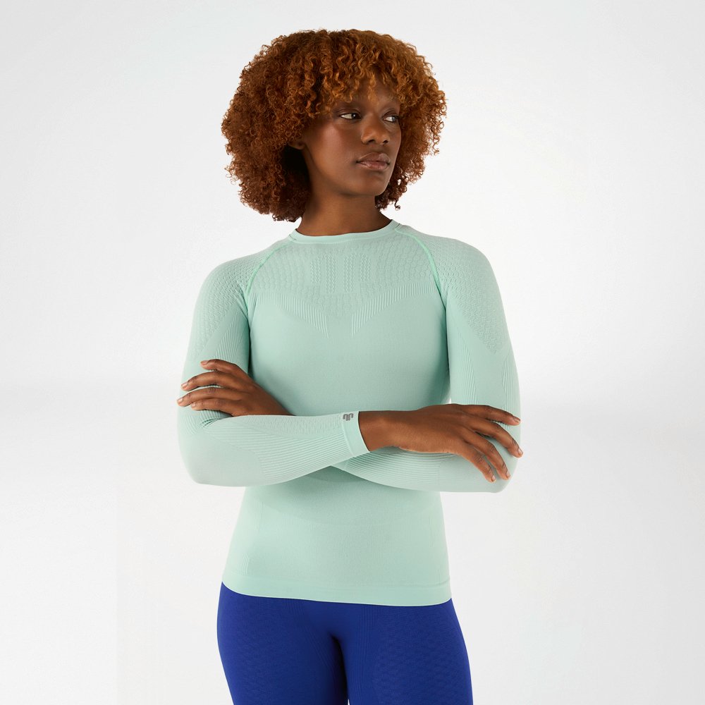 Donna con maglia a maniche lunghe verde chiaro aderente e braccia incrociate, vista frontale