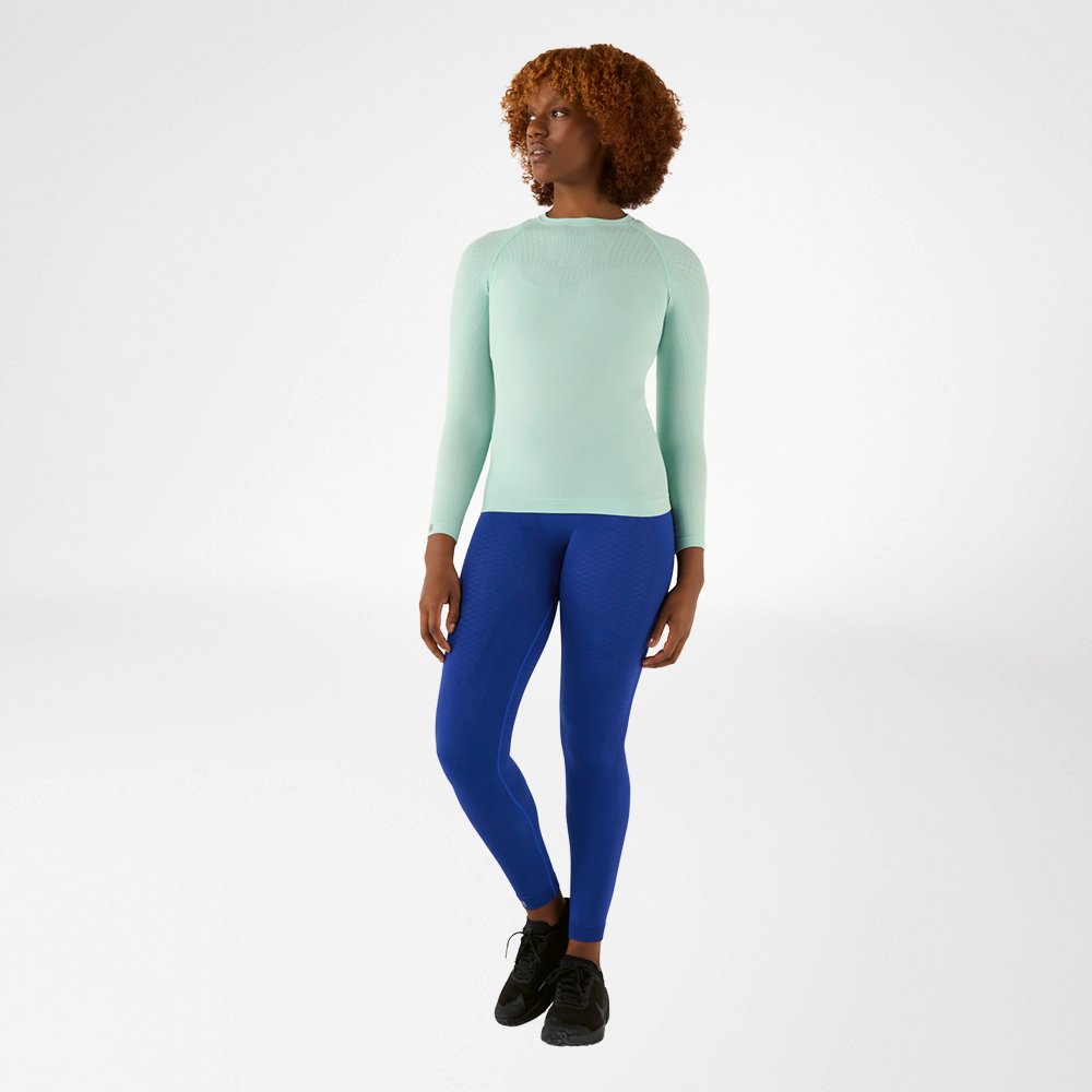 Donna con maglia a maniche lunghe blu aderente e pantaloni a compressione blu, vista frontale