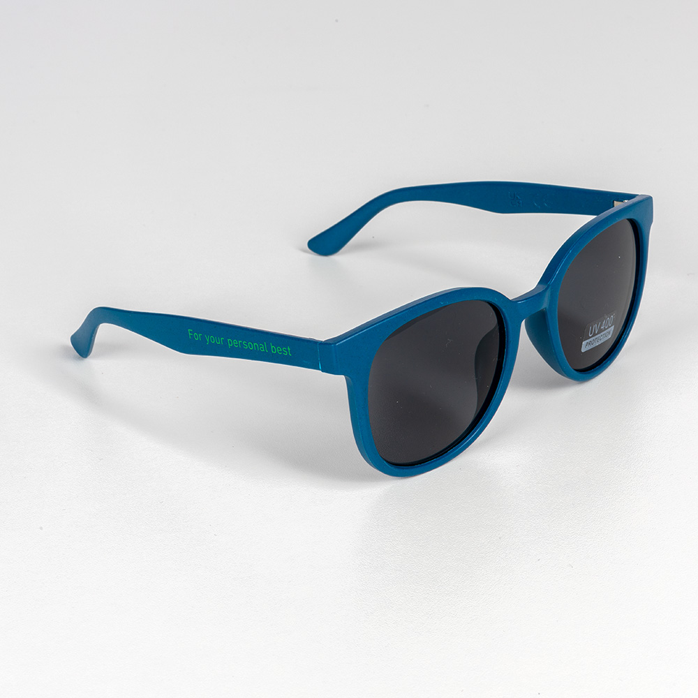 Occhiali da sole verde-blu con lenti scure e scritta “For your personal best” sulle aste. Appoggiati su uno sfondo bianco.