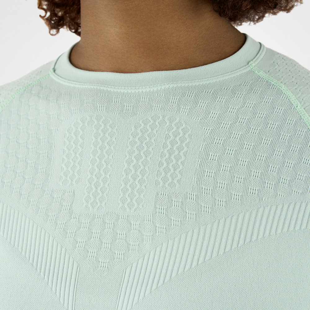 Primo piano di una maglia a compressione verde menta con tessuto strutturato, che mette in evidenza la consistenza e i dettagli del materiale.