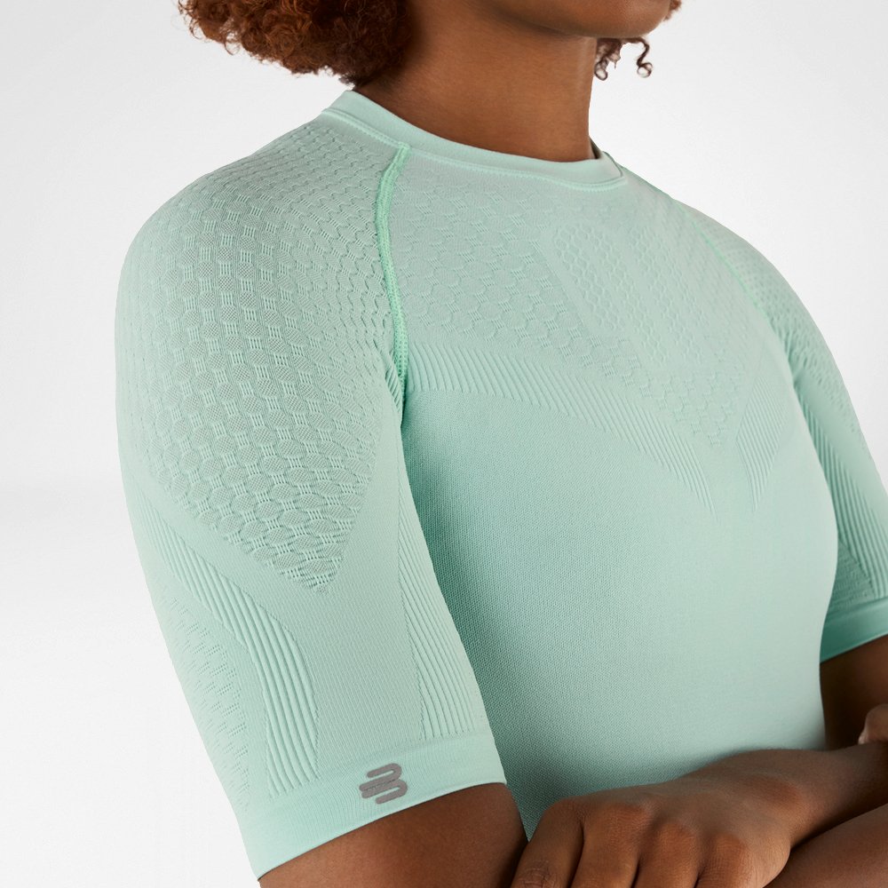 Primo piano laterale di una maglia a compressione verde menta con tessuto strutturato dettagliato sulla spalla e sul braccio.