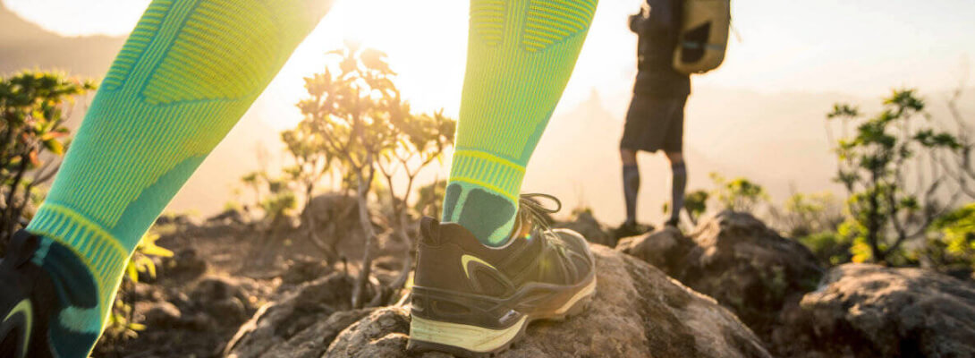Zoom sulle gambe di un escursionista che indossa calze a compressione verde chiaro per il trekking