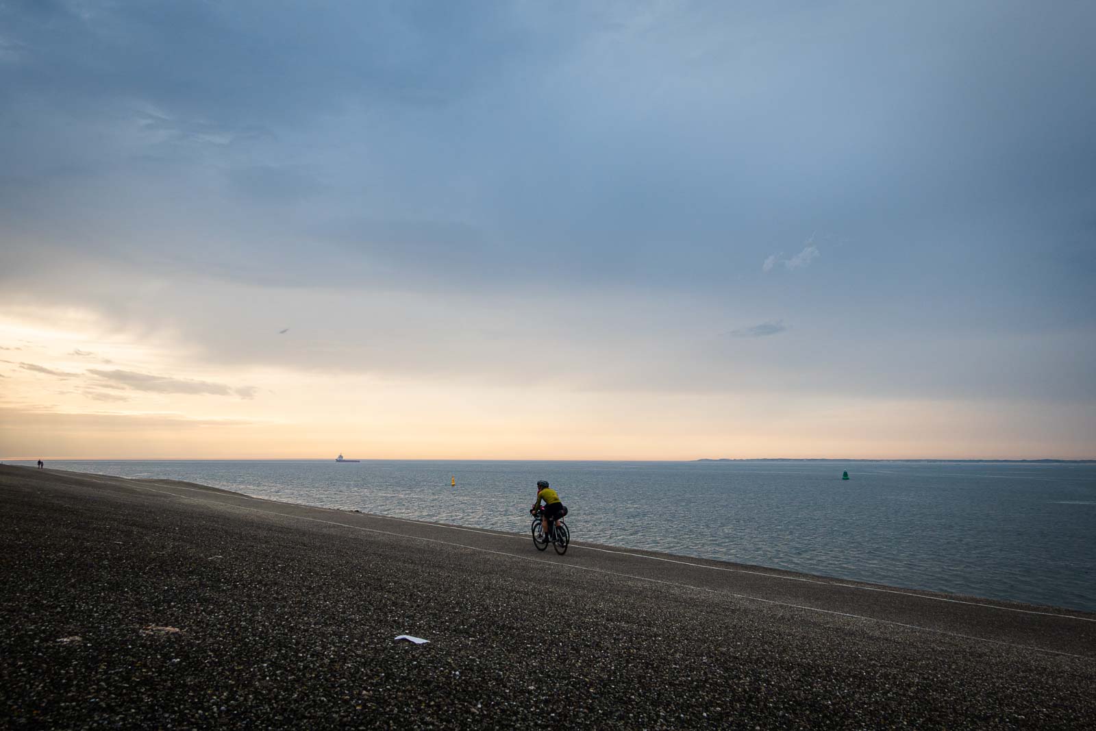 I ciclisti in riva al mare pedalano verso il tramonto Due partecipanti alla Race around the Netherlands pedalano verso il sole della sera.