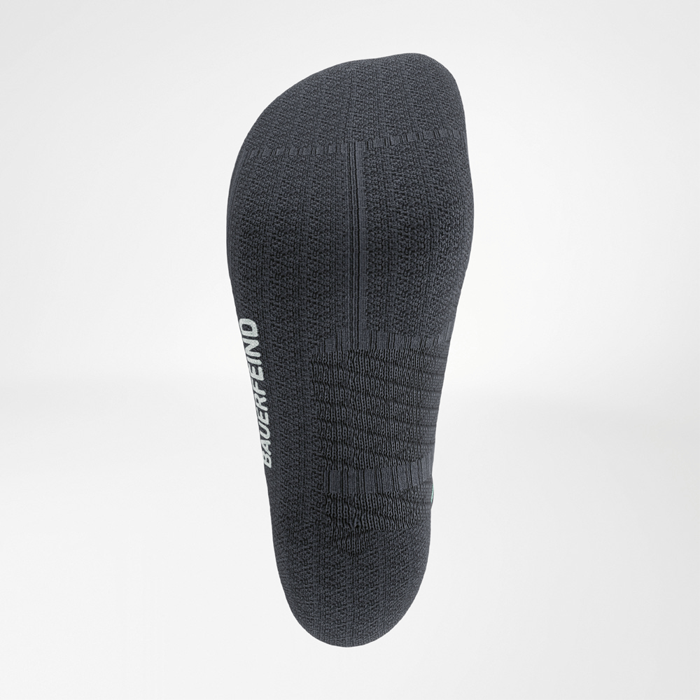 Vista dettagliata della suola di una calza nera Run Performance Midcut. Il logo Bauerfeind intrecciato è visibile sul lato e la struttura a maglia garantisce presa e ammortizzazione mirata.