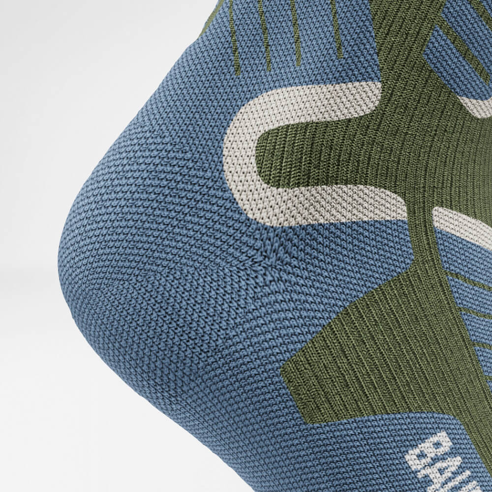 Primo piano del tallone di un calzino a compressione da sci verde con design a maglia ergonomico e traspirante per il massimo supporto e comfort durante attività sportive invernali intense.