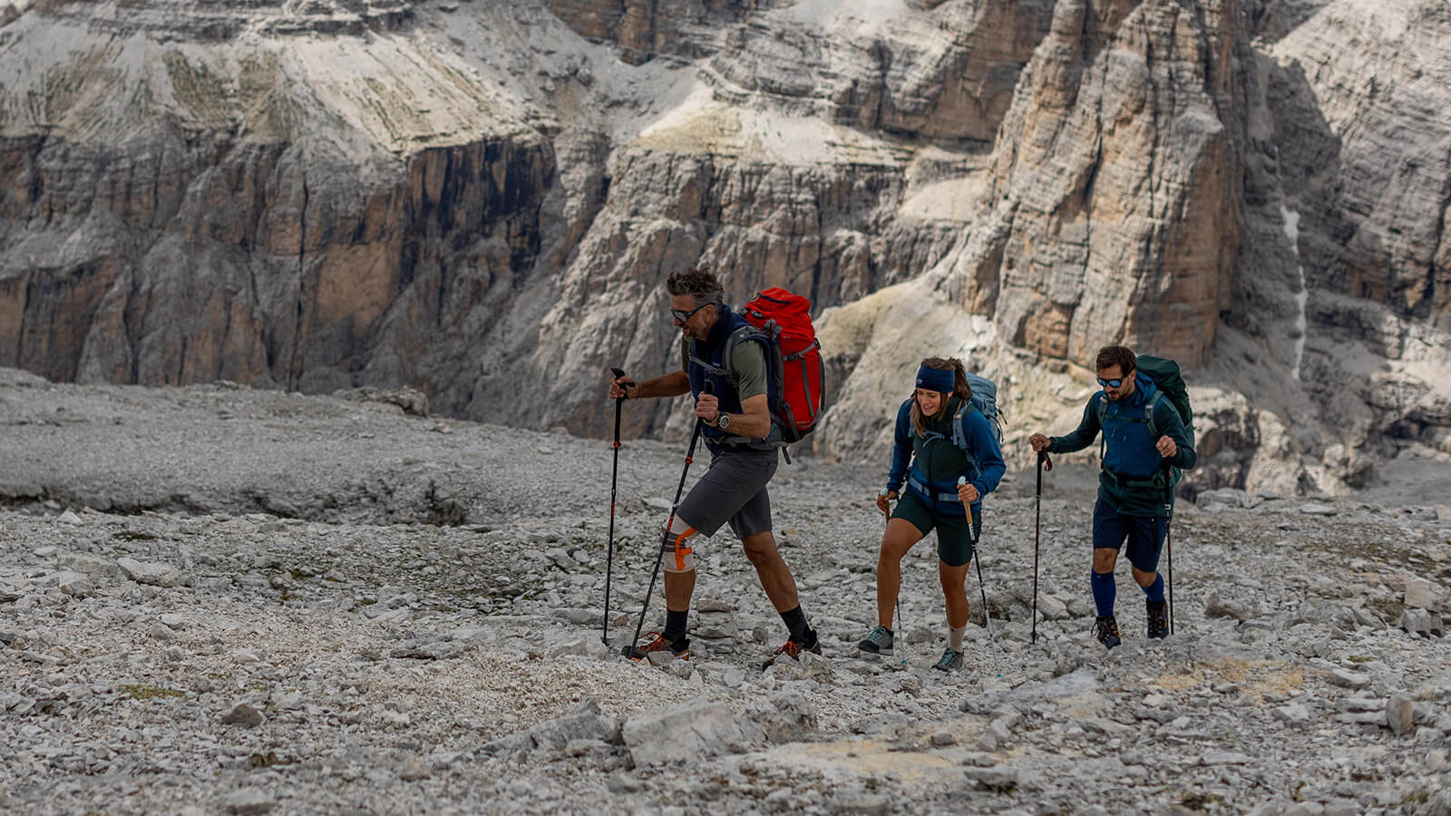 Escursione avventurosa nelle Dolomiti Un gruppo di tre escursionisti nelle Dolomiti cammina su un campo roccioso con uno sfondo montano.