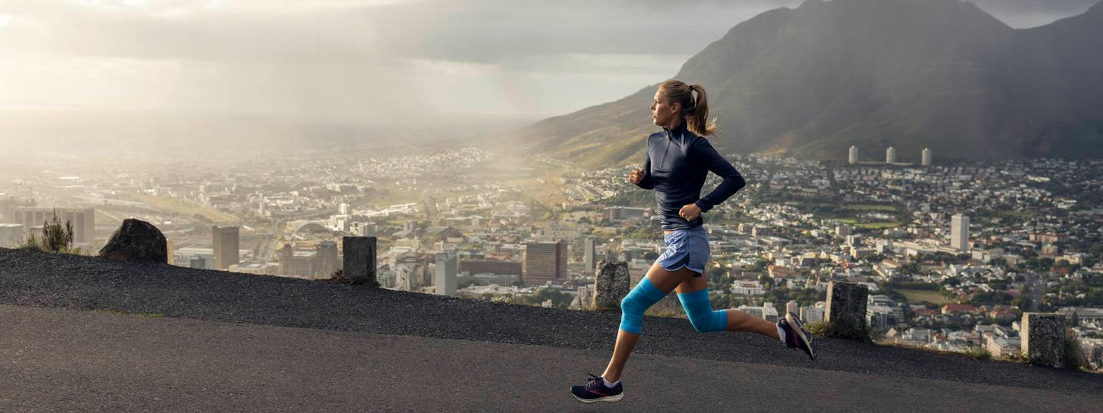 La donna corre sulle montagne in città in estate