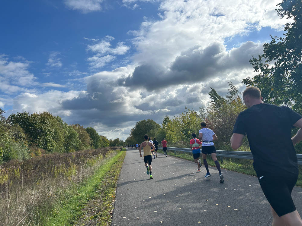 Runner durante una mezza maratona su un percorso asfaltato in una giornata autunnale soleggiata