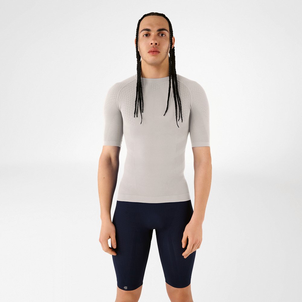 Un uomo in abbigliamento compressivo grigio argento in piedi che guarda la fotocamera.
