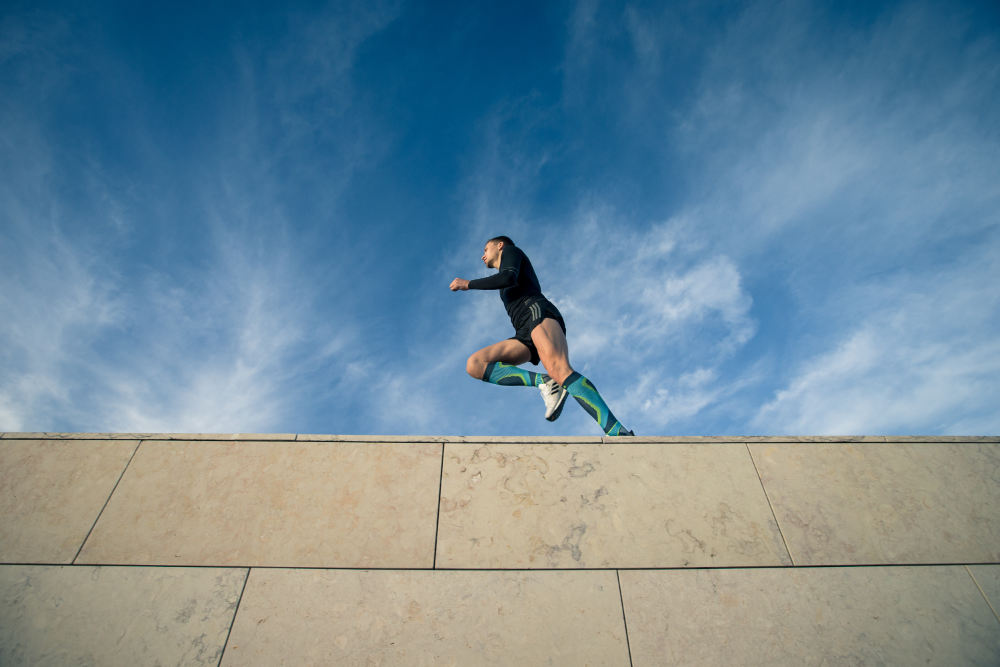 Prospettiva di rana forte: vista di un muro su cui corre un uomo con calze a compressione colorate