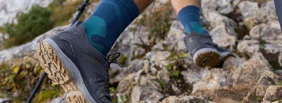 Calzini da trekking merino-lunghezza durante l'arrampicata La persona sale su una montagna sopra le pietre e indossa calzini da trekking di media lunghezza