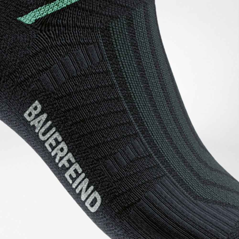 Dettaglio delle Run Performance Midcut Socks nere con elemento verde nell’area dell’arco plantare. La vista ravvicinata mostra la zona di compressione strutturata che offre supporto e stabilità mirati.