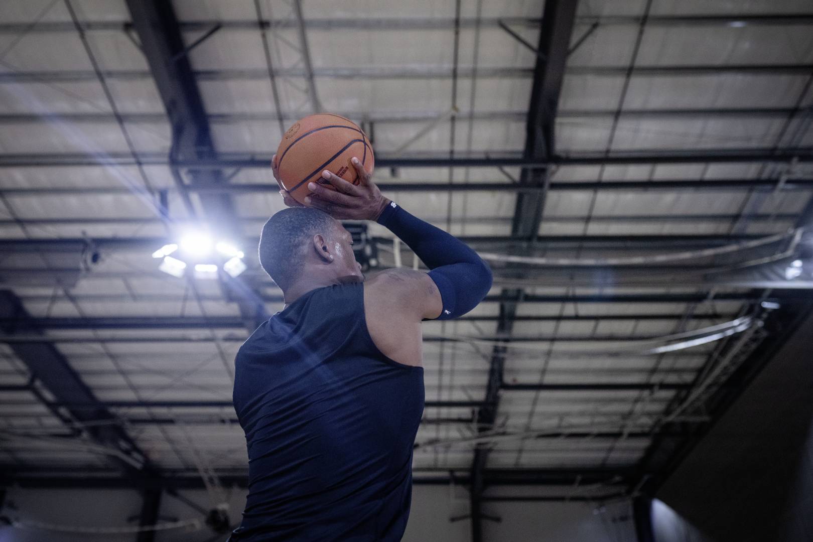 I giocatori di basket con un armatore blu in una sala sportiva iniziano con le mani sopra la testa fino al tiro