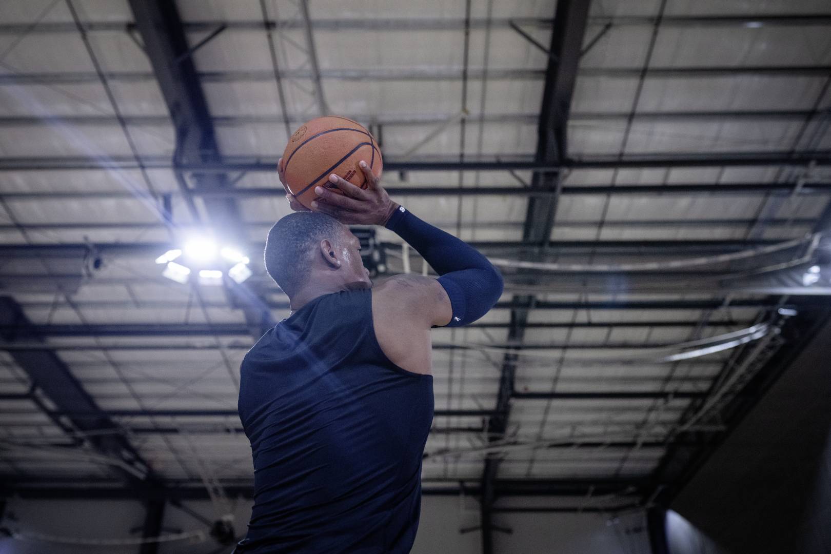 Il nostro sonno di tiro per i momenti speciali: il braccio di compressione Dormi "Dirk Nowitzki" I giocatori di basket con un armatore blu in una sala sportiva iniziano con le mani sopra la testa fino al tiro