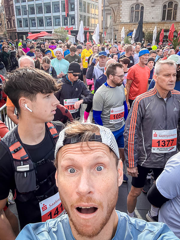 Selfie di un partecipante alla partenza della Maratona Mitteldeutscher 2024 a Halle Un partecipante entusiasta scatta un selfie poco prima della partenza della Maratona Mitteldeutscher 2024 a Halle. Intorno a lui, molti altri corridori sono riuniti, pronti per la mezza maratona.