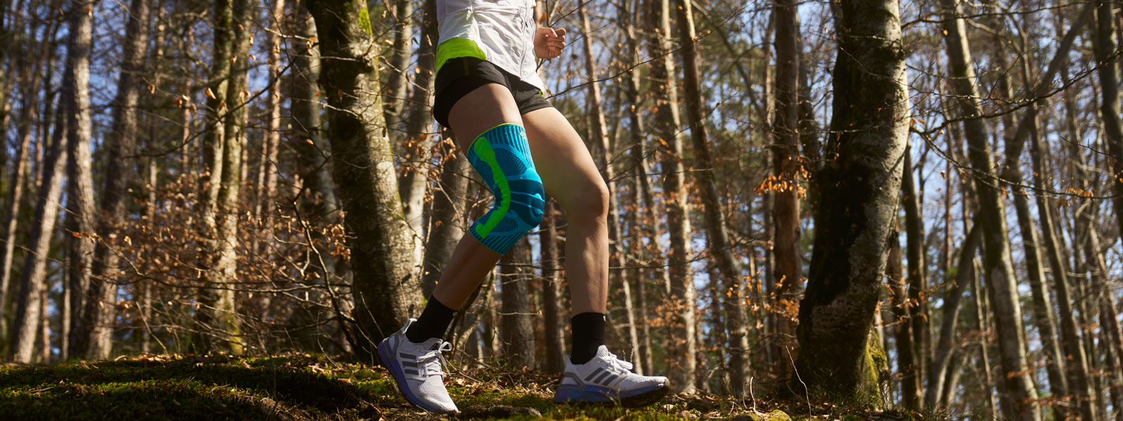 Anna Hahner corre lungo il sentiero forestale con una fascia al ginocchio