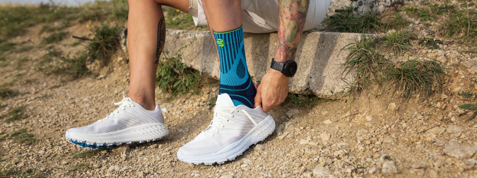 Corri ancora più sicuri e dolore senza dolore con bendaggio tendineo di Achille L'uomo tira una scarpa da corsa su una pietra su una pietra sopra la sua fascia di tendine di Achille