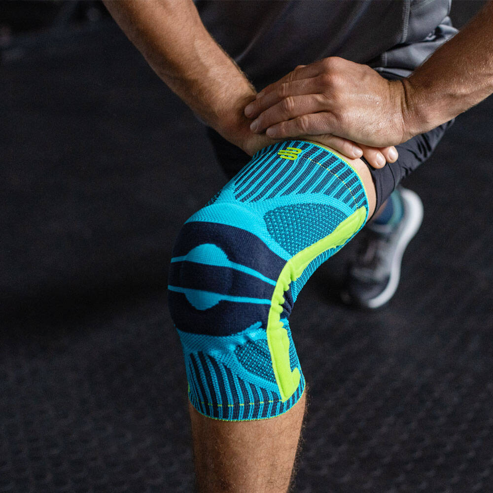 Supporto sportivo del ginocchio per gli squat - allenamento per il fitness L'uomo si piega il ginocchio e indossa un supporto per il ginocchio sportivo