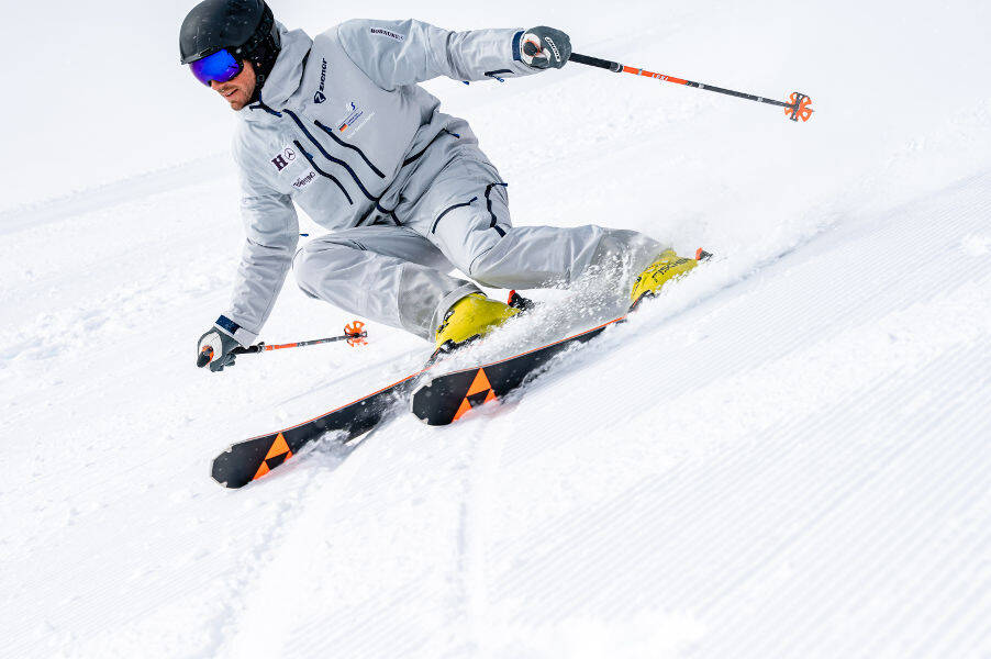 Gli sciatori con un abito grigio con una luce inclinata leggera davanti a lui possono essere riconosciuti dallo schema scanalatura delle piste stagnanti