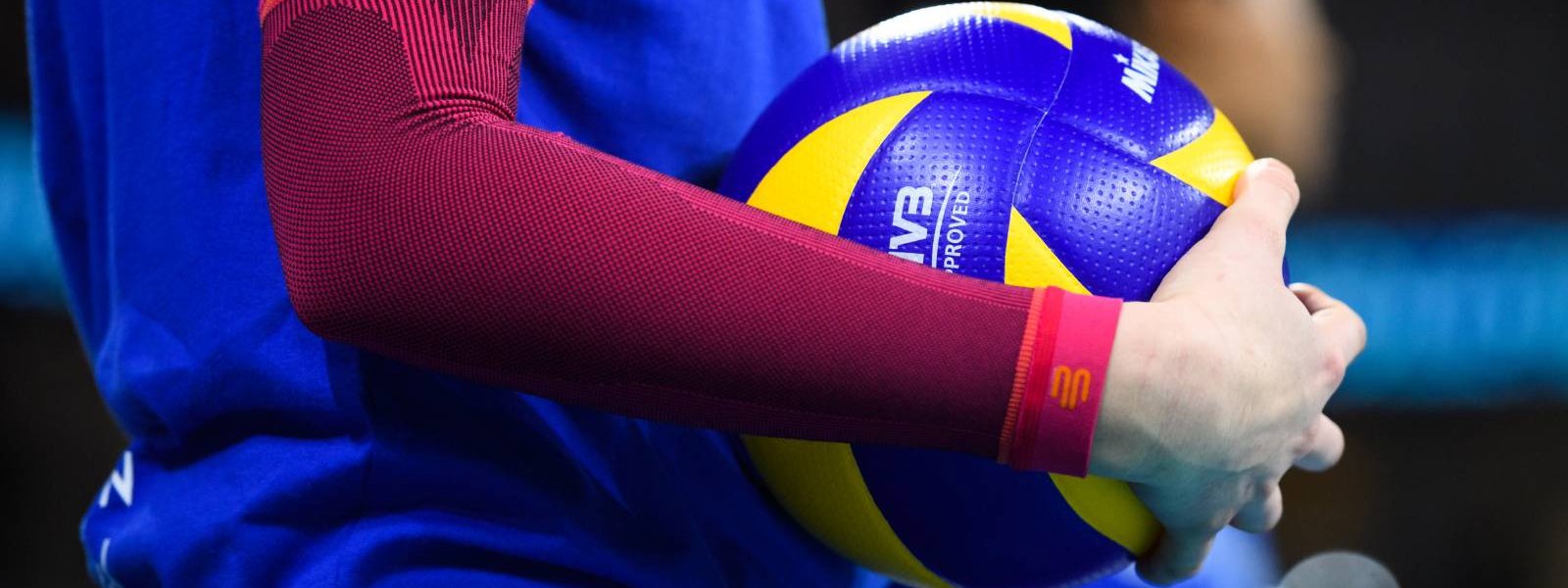 Pallavolo con maniche a braccio Il giocatore di pallavolo con maniche a braccio rosa ha una pallavolo in mano