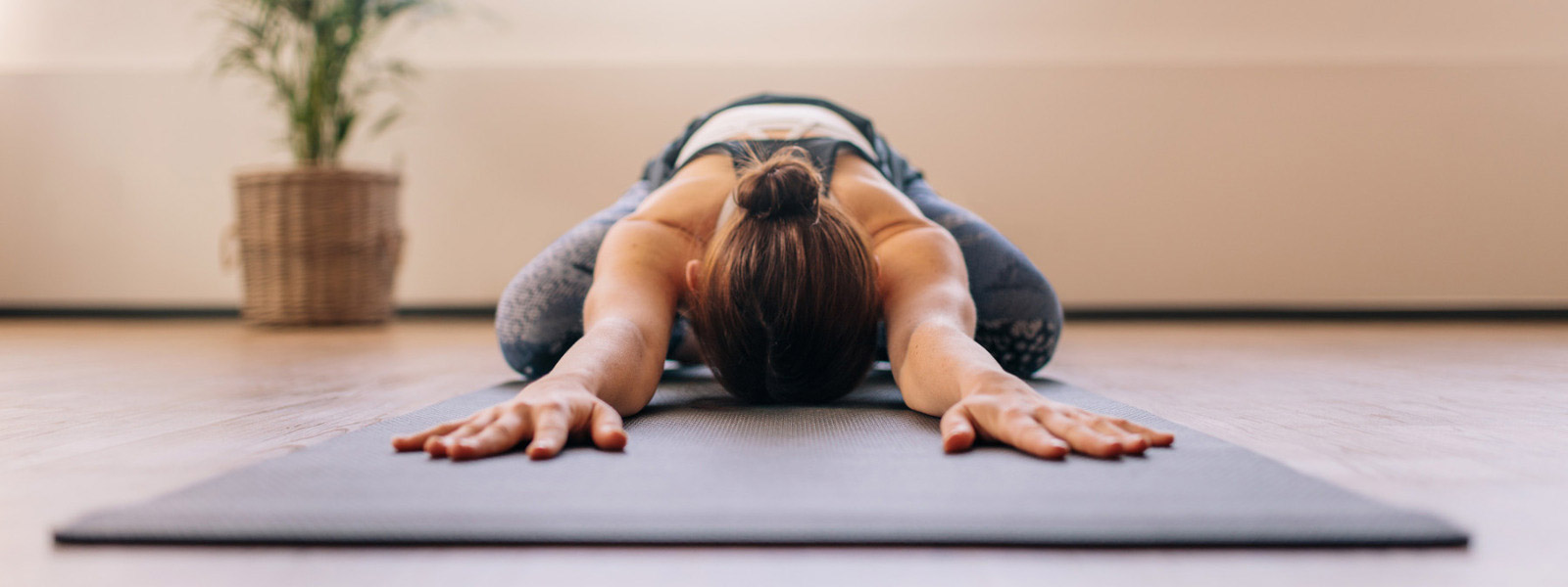 Lo yoga contro il mal di schiena può essere molto rilassante Deep -relaxed Woman ha rimesso la testa tra le braccia sul tappeto