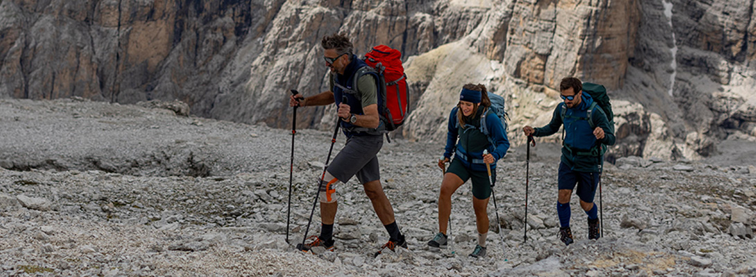 Ginocchiera da esterno per l'alpinismo Tre arrampicatori, il primo indossa una ginocchiera da esterno