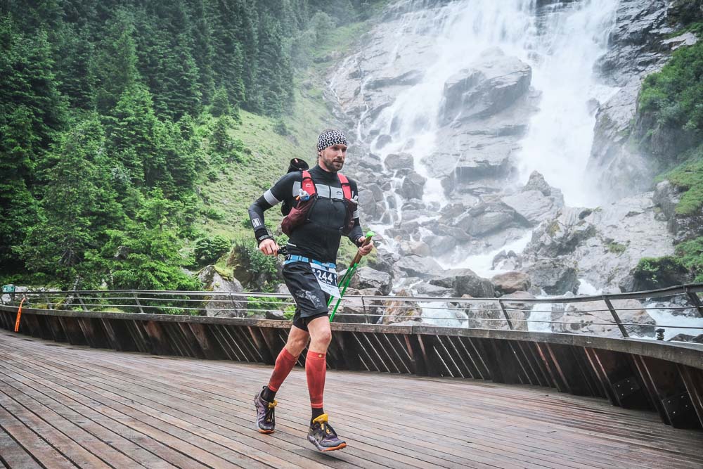 Lord Jens Kramer durante un'ultramaratona su un ponte di legno davanti a una cascata