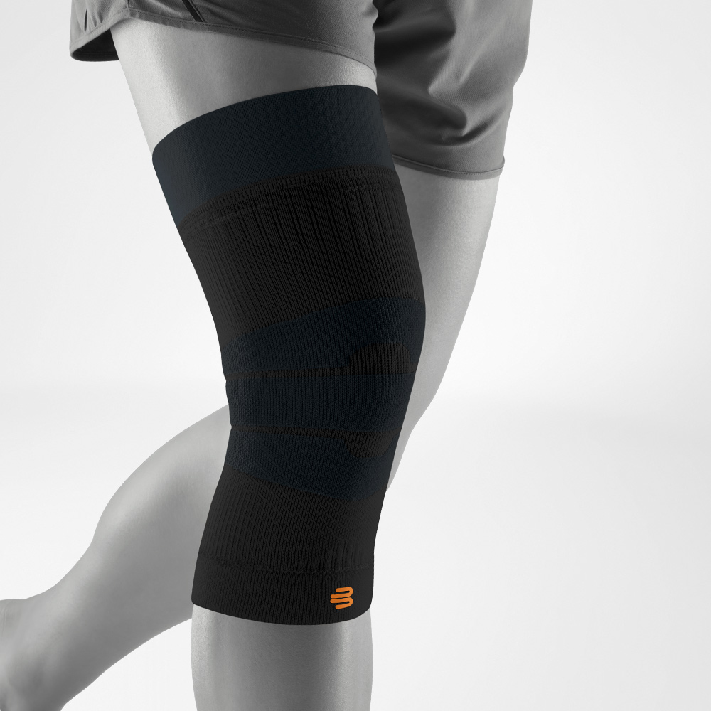 Ginocchiera nera vista laterale indossata sulla gamba. La maglia a compressione flessibile sostiene l’articolazione durante attività all’aperto come corsa, trekking o allenamento.