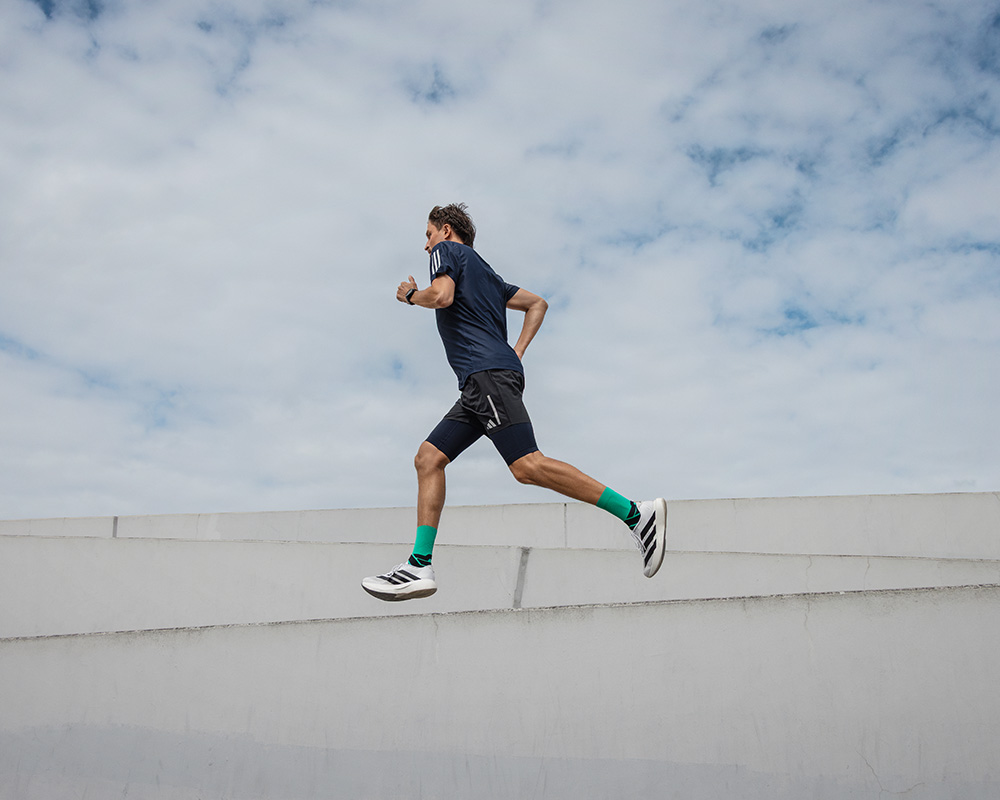 Prospettiva di rana forte: vista di un muro su cui corre un uomo con calze a compressione colorate