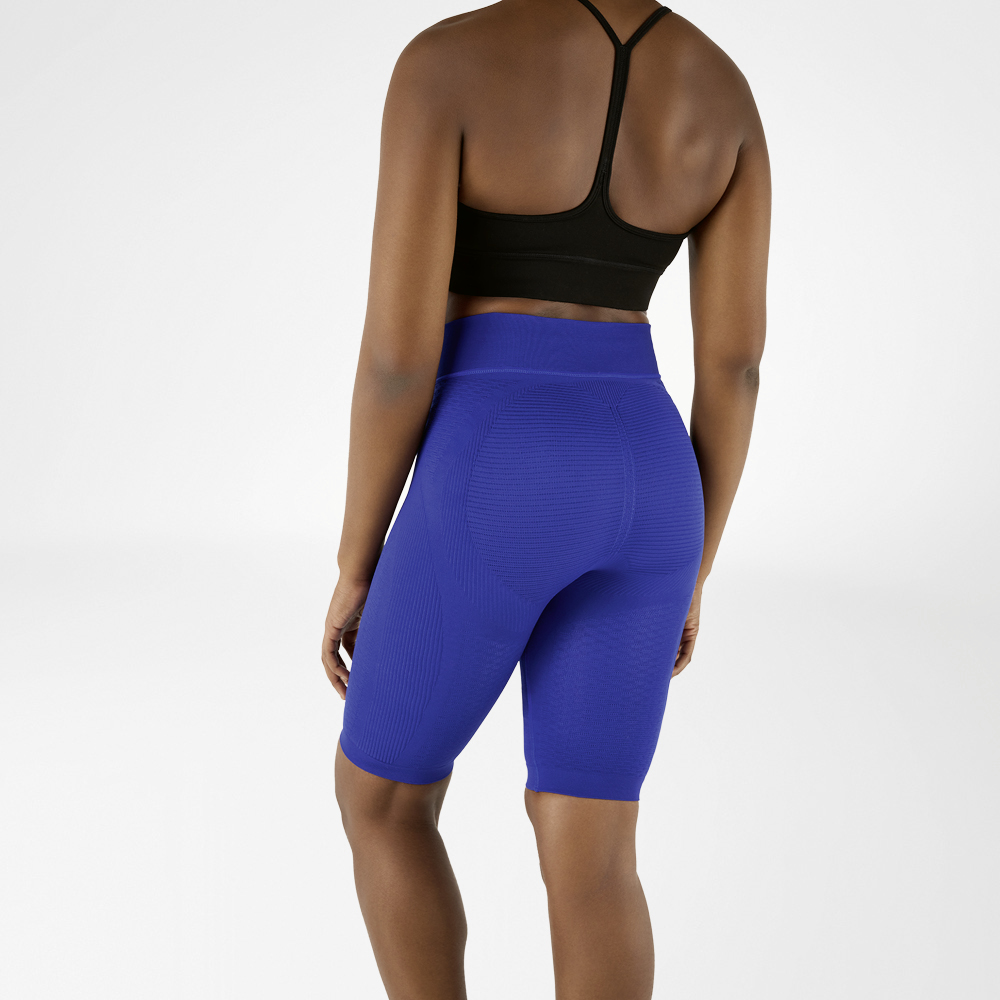 Completo sportivo da donna con leggings corti a compressione di colore blu navy Donna fotografata da dietro con reggiseno sportivo nero e leggings compressivi blu al ginocchio.