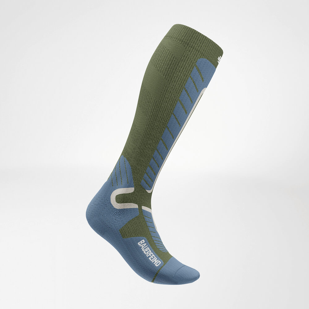 Vista laterale di un calzino a compressione da sci verde fino al ginocchio con motivo a maglia rinforzato per stabilità e comfort ottimali durante gli sport invernali.