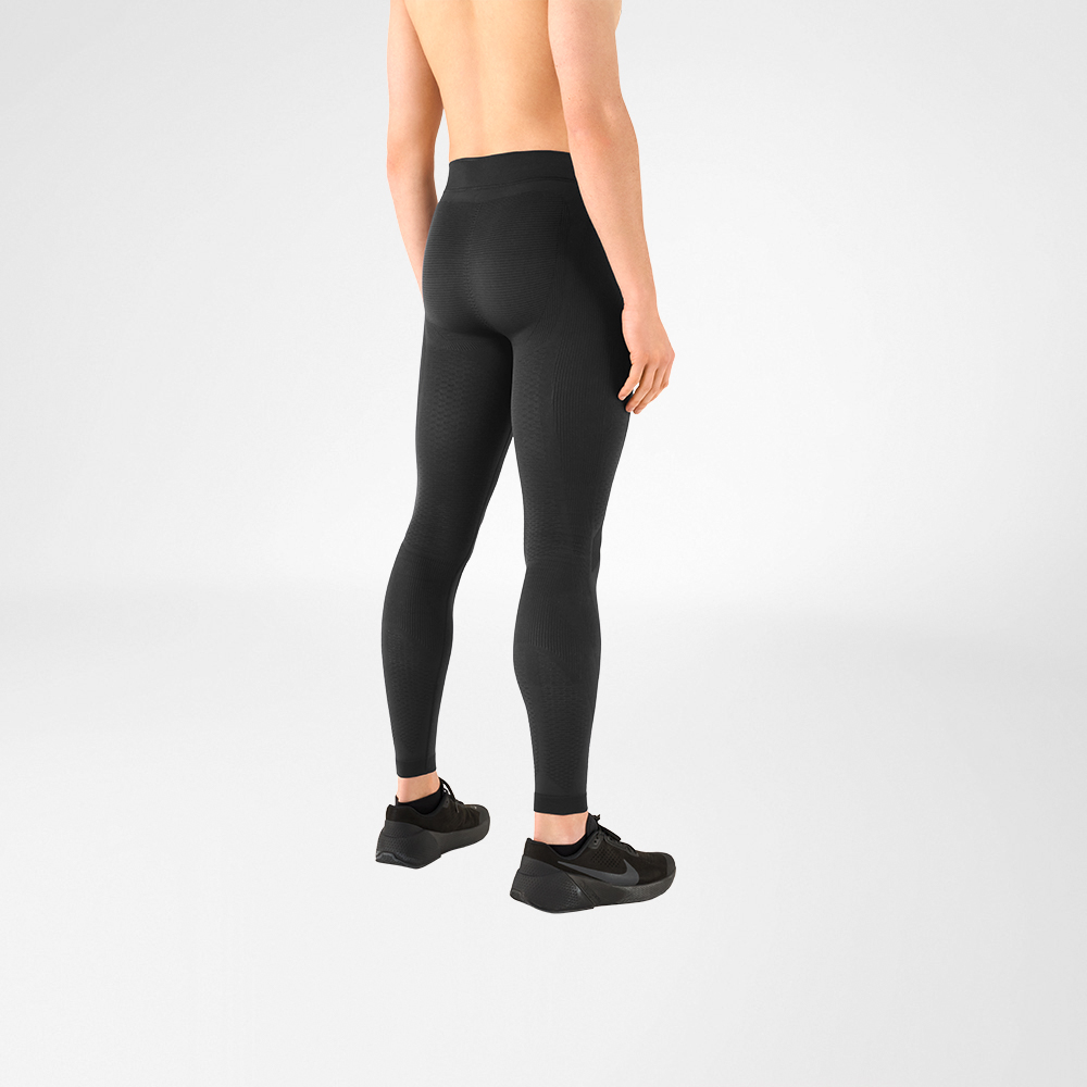 È possibile vedere un dettaglio di un uomo a torso nudo che indossa scarpe sportive nere e pantaloni a compressione grigio antracite. È in piedi di lato e dà le spalle alla telecamera.
