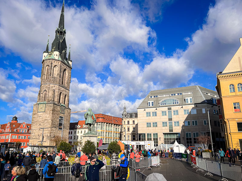 La piazza del mercato a Halle durante la Maratona della Germania Centrale con la Torre Rossa sullo sfondo. Corridori e spettatori si radunano nella piazza del mercato di Halle prima della partenza della Maratona della Germania Centrale. Sullo sfondo si erge la Torre Rossa, un punto di riferimento della città.