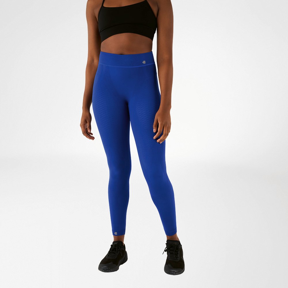 Una donna con reggiseno sportivo nero e pantaloni sportivi blu navy a vita alta, lunghi fino alla caviglia